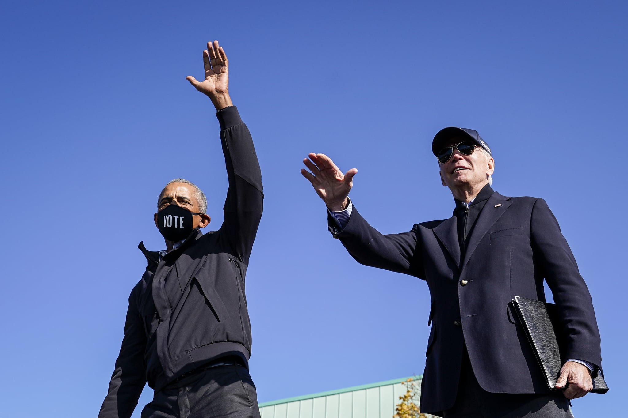 FLINT, MI - OCTOBER 31: Former U.S. President Barack Obama and Democratic presidential nominee Joe Biden wave to the crowd at the end of a drive-in campaign rally at Northwestern High School on October 31, 2020 in Flint, Michigan. Biden is campaigning with former President Obama on Saturday in Michigan, a battleground state that President Donald Trump narrowly won in 2016. (Photo by Drew Angerer/Getty Images)